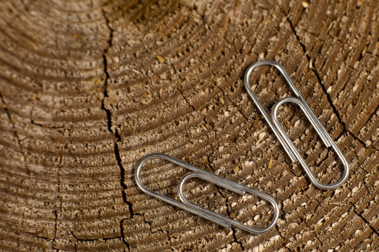 Several paper clips on a wooden background. Metal stationery accessories for education or business.