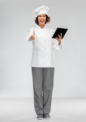 cooking, culinary and people concept - happy smiling female chef in toque with tablet pc computer showing thumbs up over grey background