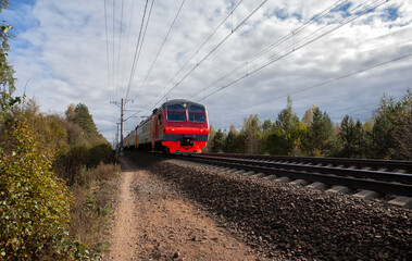 Red electric train rides on the rails of the railway.Summer, Sunny day.
