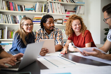 Young architect colleagues are analyzing blueprints while working on a new project