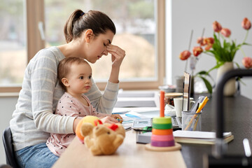 remote job, multi-tasking and family concept - tired mother with baby working at home office