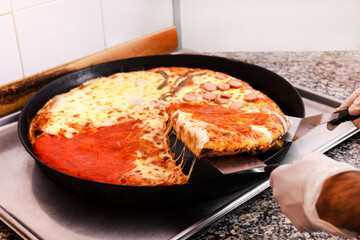 Chef taking a slice of pizza from a baking tray