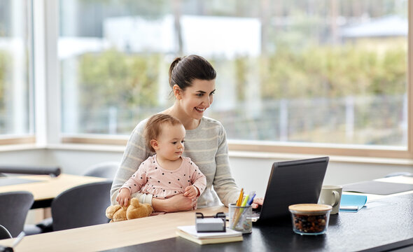 remote job, multi-tasking and family concept - happy smiling mother with baby and laptop working at home office