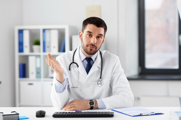 healthcare, medicine and people concept - male doctor with stethoscope having video conference at...