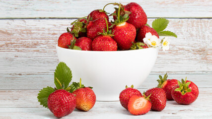 bowl of fresh strawberries on white wooden table with copy space