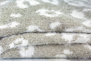 a stack of grey knitwear with a white pattern as the background