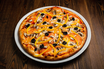 Mushroom, yellow pepper, black olives, tomato and cheese pizza, wooden background, low key