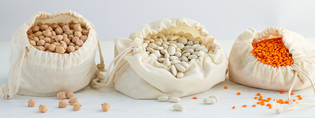 Supplies cotton bags of healthy groats close-up (chickpeas, lentils, beans)
