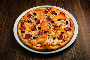 Pepperoni, mushroom, black olives, tomato and cheese pizza, wooden background, low key