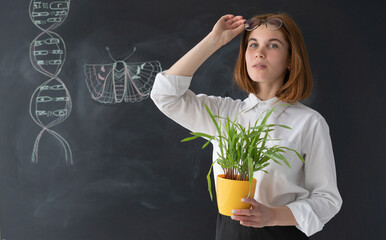 Young teacher holds a pot with a plant for study.