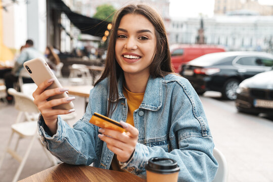 Image of smiling woman using cellphone and holding credit card