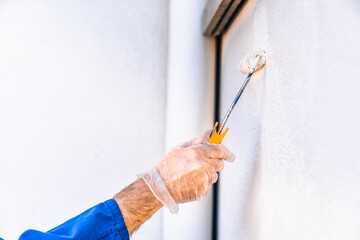 Painter painting the wall of the house. Hand holding a roller with white paint. Concept of painting and reforming the house.