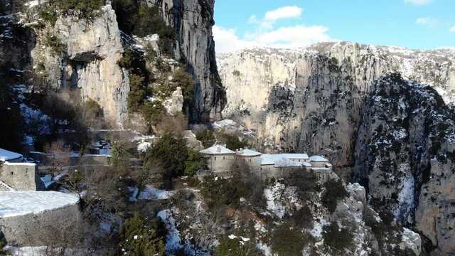 AERIAL View of snowy Agia Paraskevi monastery in Zagoria Greece with Vikos Gorge in background