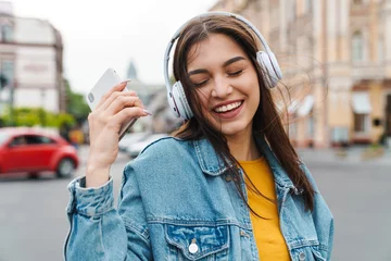 Gordijnen Image of woman listening music with smartphone and wireless headphones © Drobot Dean