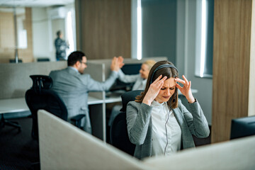 Stressed customer service operator, colleagues in the background high five.