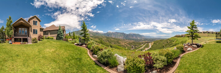 Panorama of the backyard of home with landscaped grassy lawn and lush plants