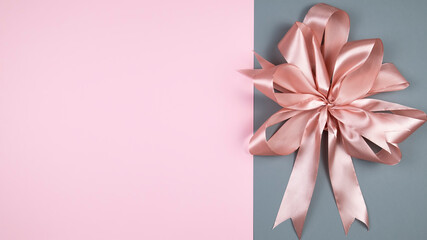 Pink satin bow on a color background. Decorative background. Top view, space for text, copyspace