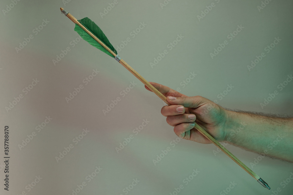 Poster Hand holding old green arrows in the color light. Beautiful old arrow minimal in neon light. Minimalism retro style concept. Background pattern for design.