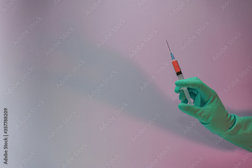 Poster Beautiful hand holding creative syringe with red vaccine in the neon light. Minimalism retro style concept. Background pattern for design...