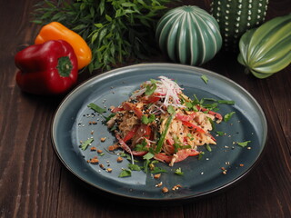 Asian rice noodles salad with chicken meat, tomatoes, sesame, radishes, nuts and greens