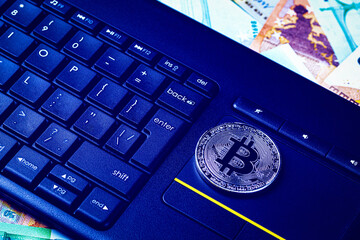 Euro bills, black keyword and metal souvenir bitcoin. The concept of electronic money, online...
