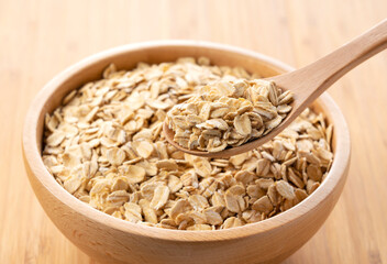 Oatmeal and wooden spoon set against a wooden background