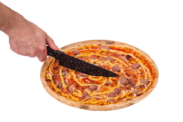 Man's hand cuts the salsiccia pizza with a kitchen knife, angle view. Italian pizza with beef...