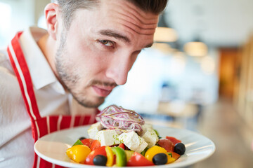 Kellner serviert Griechischen Salat als Vorspeise