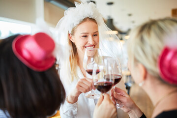 Glückliche Braut beim Anstoßen mit Glas Wein