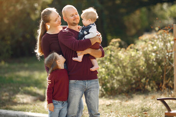 Fototapeta premium Family in a autumn park. Woman in a red sweater. Cute childrens with parents