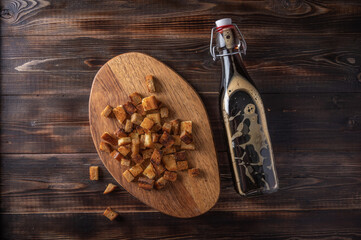Top view homemade tradishional russian kvass in bottle and rusk on cutting board on wooden background. Wonderful healthy refreshing drink for summer