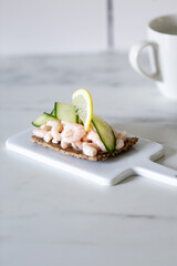 shrimp and cucumber open sandwich on marble background with copy space