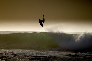 In the early dawn light a surfer does an aerial at SuperTubes Jeffreys Bay, South Africa