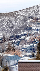 Fototapeta na wymiar Vertical crop Park City Utah mountain in winter with colorful homes that sit on snowy slopes