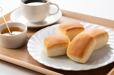 Dinner rolls, coffee and honey on a wooden tray