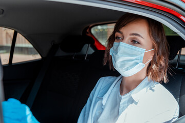 Fototapeta na wymiar woman in medical mask and gloves sitting in taxi during covid-19 pandemic