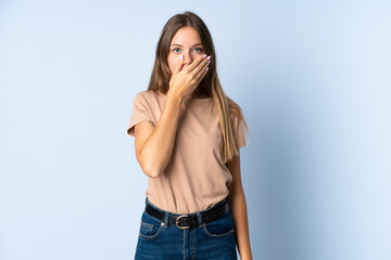 Young Lithuanian woman isolated on blue background covering mouth with hand