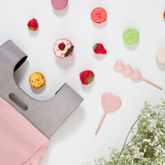 Beautiful set for design, advertising or background, cupcakes, lollipops, macaroons and leather bright backpack laid out on a gray background.
