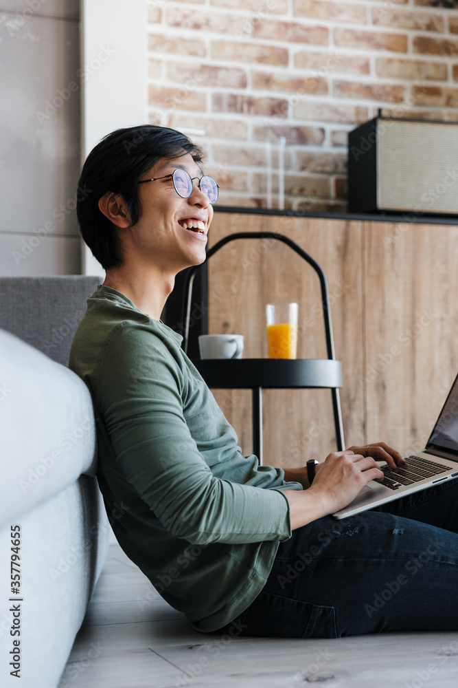 Sticker Image of laughing asian man working with laptop while sitting