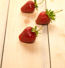 Three strawberries on a wooden table close-up