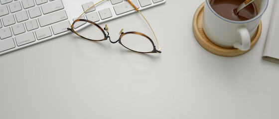 Copy space on white worktable with glasses, computer keyboard and hot cocoa cup