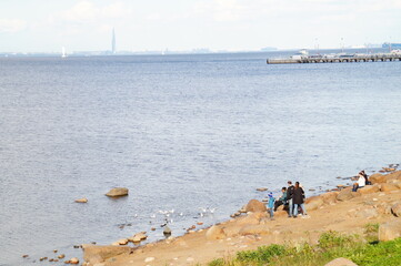 people walk along the rocky shore of a large river