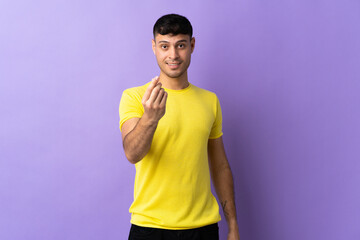 Young Colombian man isolated on purple background making money gesture