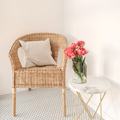 Cozy comfortable home rest space with rattan chair, white wall, mosaic tile, marble table with beautiful peony flower bouquet. Modern interior design concept. Minimalist lounge space