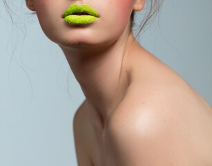 A beautiful female make-up on the lips of a green color, a close up, shoulders