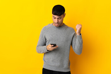 Young Colombian man isolated on yellow background surprised and sending a message