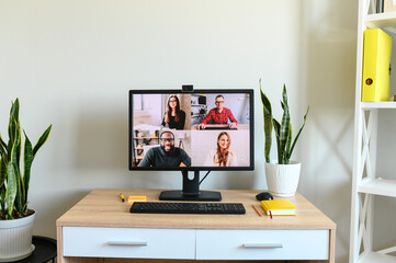 Video chat, video conference. An empty workplace in the office, PC monitor with video meeting on it. App for video connection with many people together