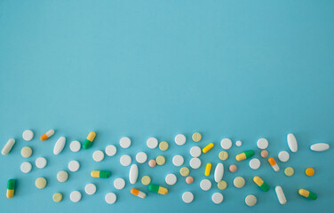 Colorful pills and capsules on a blue green background, tablets are located on the down side of the image, with a free area for text, isolated