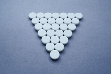 Round medicinal pills in the shape of a large triangle on a dark background, isolate.