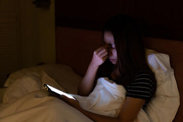 Fototapeta premium Young Asian woman using mobile phone at night and feeling eye pain and dry. Eye strain tension or blurry vision problem concept